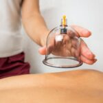 process of vacuum cupping massage, hands of the masseuse hold a jar for vacuum massage over the back